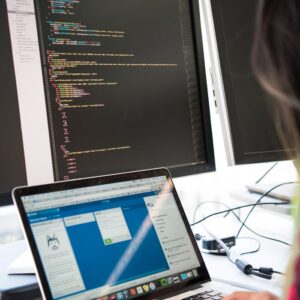 Programmer working on code across multiple screens in a modern office setting.